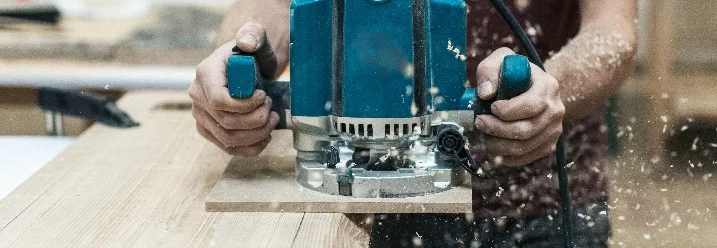 Person fräst Holz mit Oberfräse